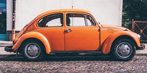 Bright orange Volkswagen Beetle car parked on cobblestone street