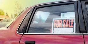 Closeup of rear window of red car with For Sale sign