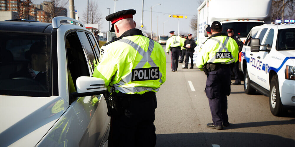 Two police officers in high-visibility jackets doing safety checks on a road in Ontario