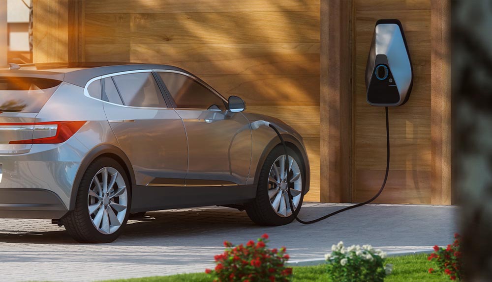 A level two charger is shown mounted on the wall of a garage