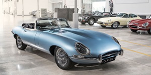 A 1960s era light blue convertible with top down, the license plate reads CLASSIC in an indoor showroom with red, yellow and black convertibles seen in the background