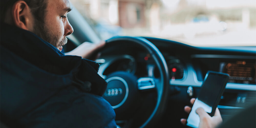 A man looks at his phone while driving 
