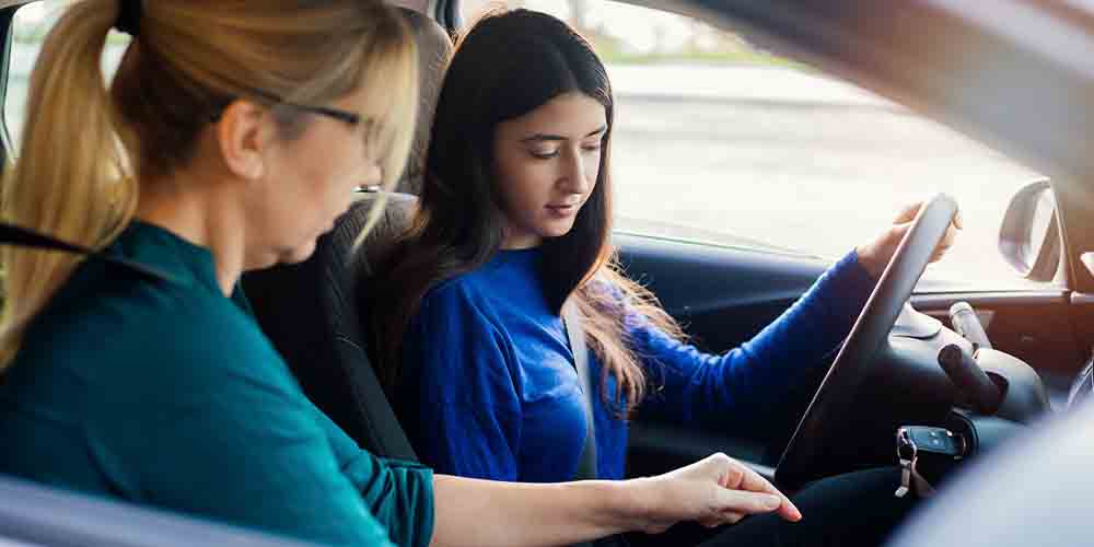 A young woman sits in the driver's seat next to an older woman