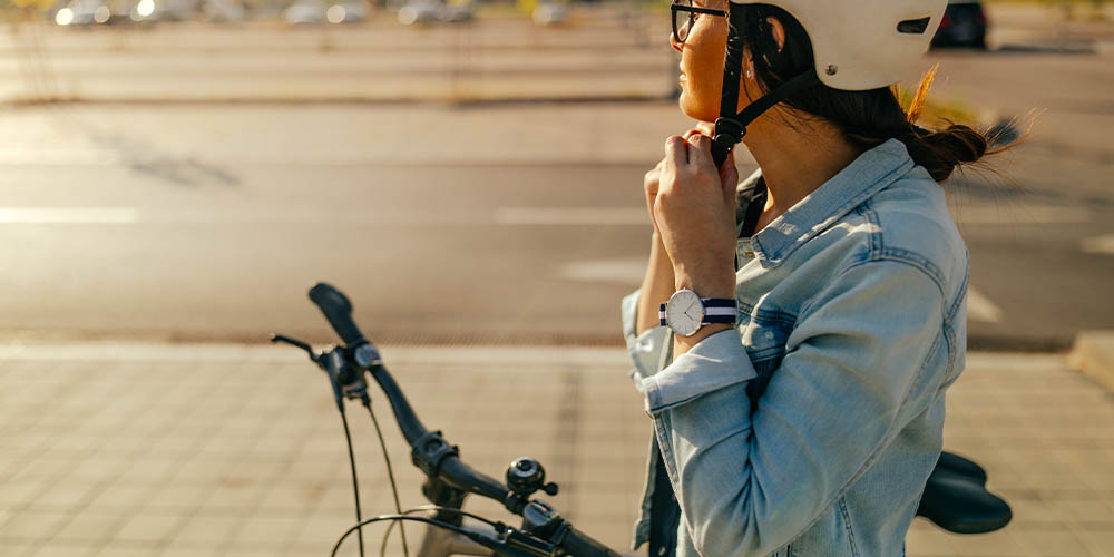 A woman fastens the strap on her bike helmet