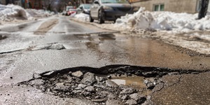 A pothole in the middle of a wet, snowy road.