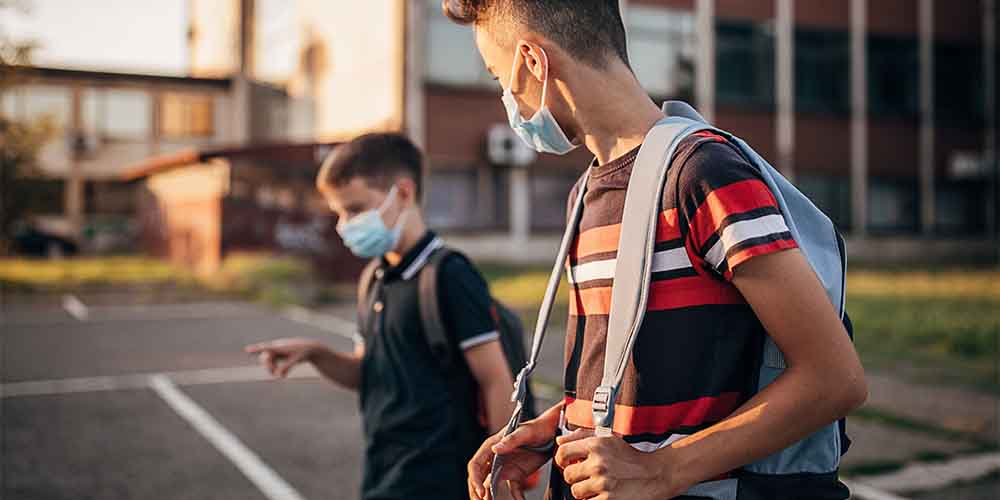 Two boys walk to school with face masks on