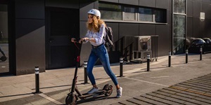A woman rides her e-scooter on a city pathway