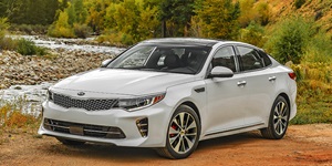 Gray Kia parked on a dirt road by a small river