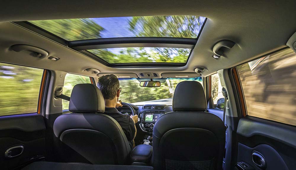Kia panoramic sunroof view from the backseat while man drives