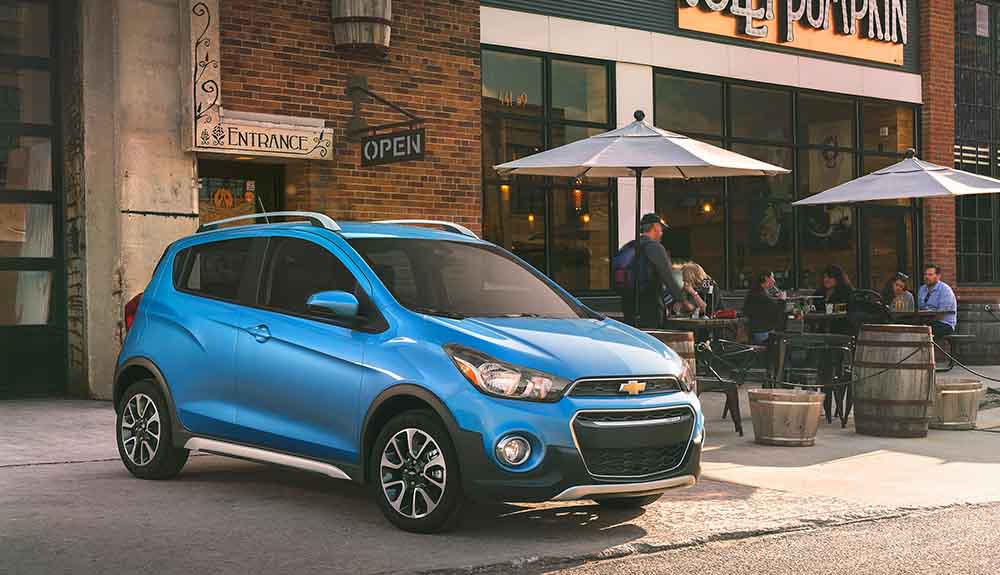 Blue Chevrolet Spark parked next to a cute restaurant patio