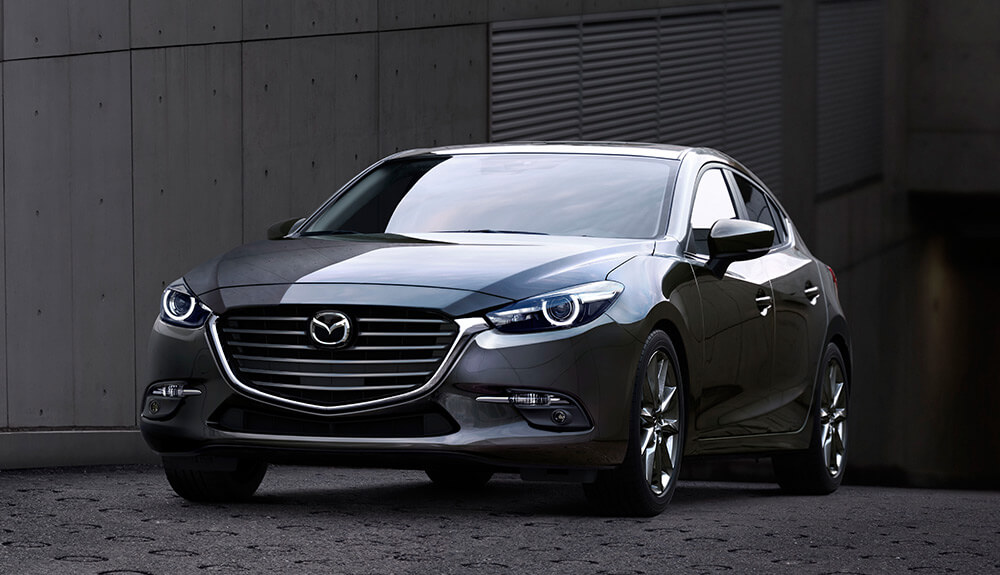 Dark gray Mazda3 GX parked in industrial setting