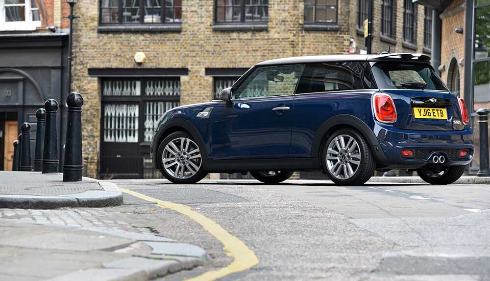 Navy Mini Cooper 3-door driving up a cute street