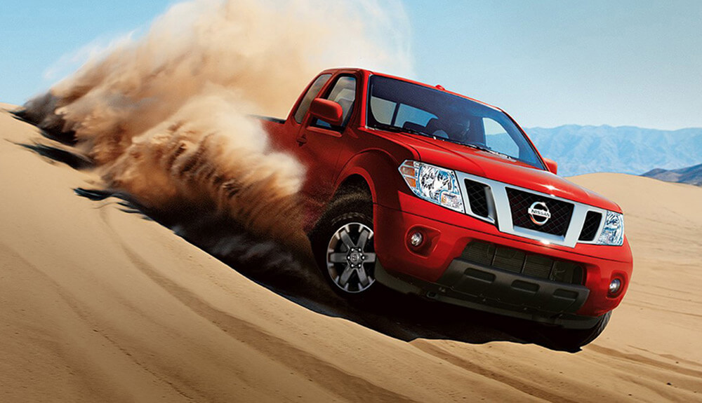 Red truck taking a powerful turn in the desert sand leaving dust in its wake
