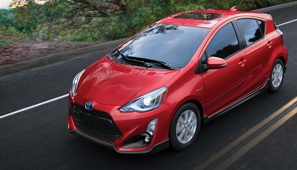 Bright red Toyota Prius driving down a road
