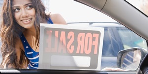 Woman looking in window of car with for sale sign
