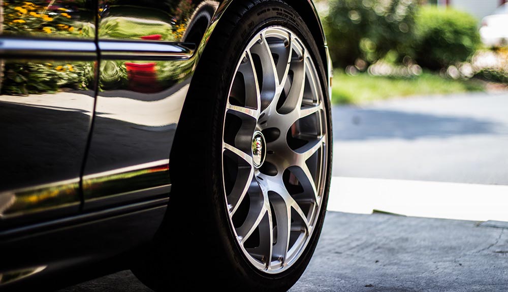 Close up of a very clean black car and back wheel outside on a sunny day