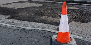 Orange pylon cone with white stripe in the middle blocks off dangerous parts of the road