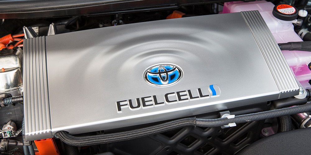 An overhead photo shows a fuel cell exposed underneath the hood of a car