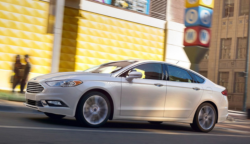 White Ford Fusion Energi Plug-in  driving down a city street