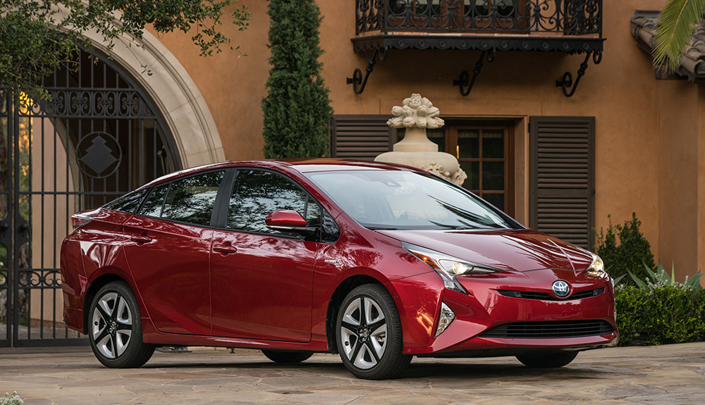 Red Toyota Prius Hybrid parked by a beautiful entrance way with metal gate