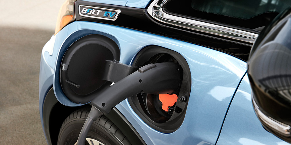 Close up of Chevy Bolt side with electric plug charged into where the gas tank traditionally is