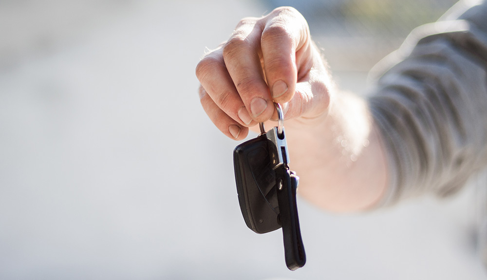 An outstretched hand holds a key fob