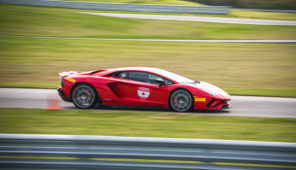 Bright red Lamborghini Aventador S Coupe speeding along with background out of focus