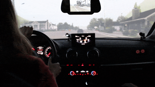 Blonde woman with orange sweater drives the test vehicle on a virtual road