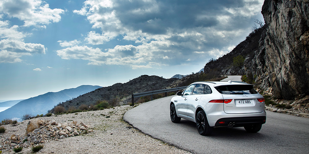Jaguar F-Pace SUV driving on the side of a scenic mountain