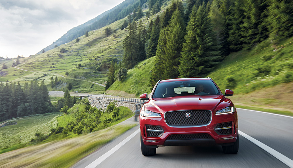 Red Jaguar Crossover SUV taking the road on the country side