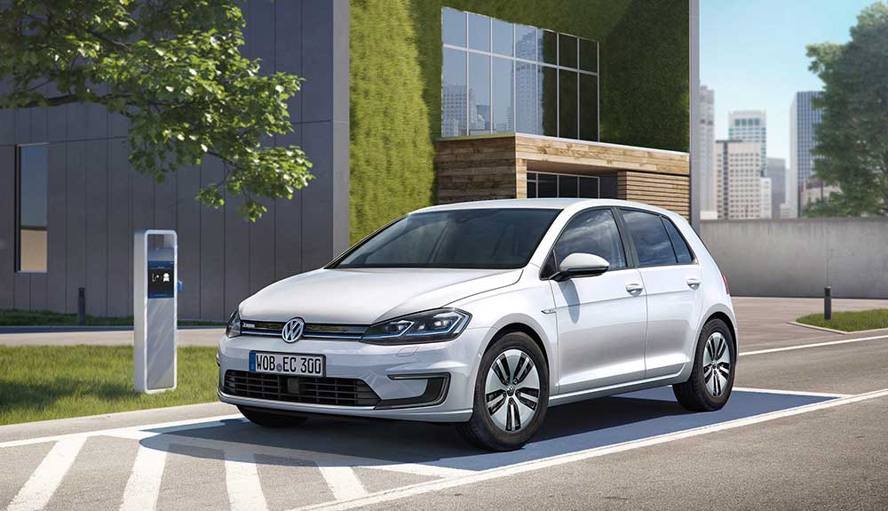 Silver e-Golf by a charging station outside of a building