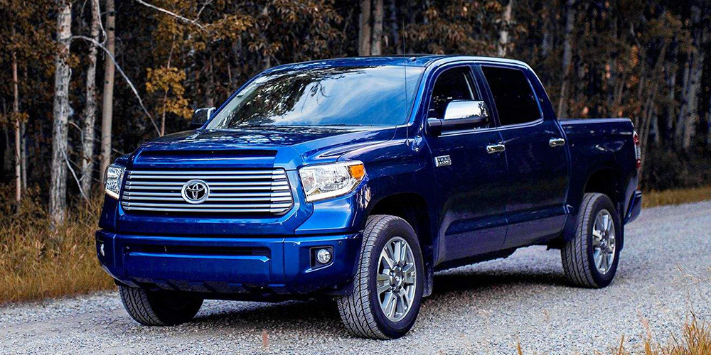 Blue 2017 Toyota Tundra on a gravel road with thin trees in the background