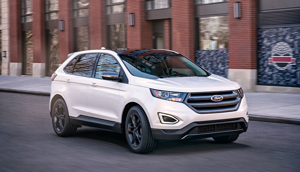 White 2018 Ford Edge zipping down an urban brick building