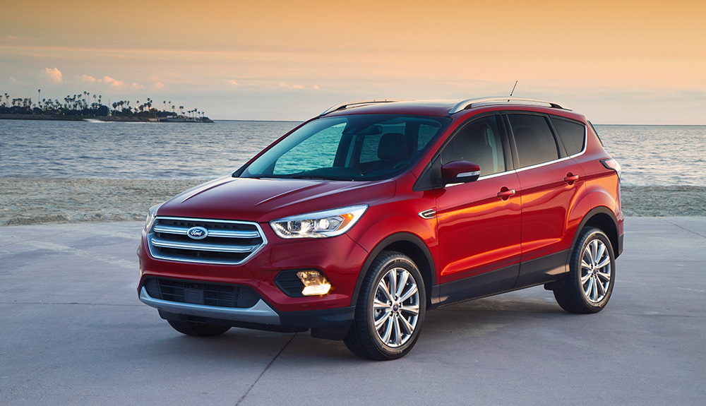 Dark red 2018 Ford Escape shimmering in the orange sunset beside a clear waterfront