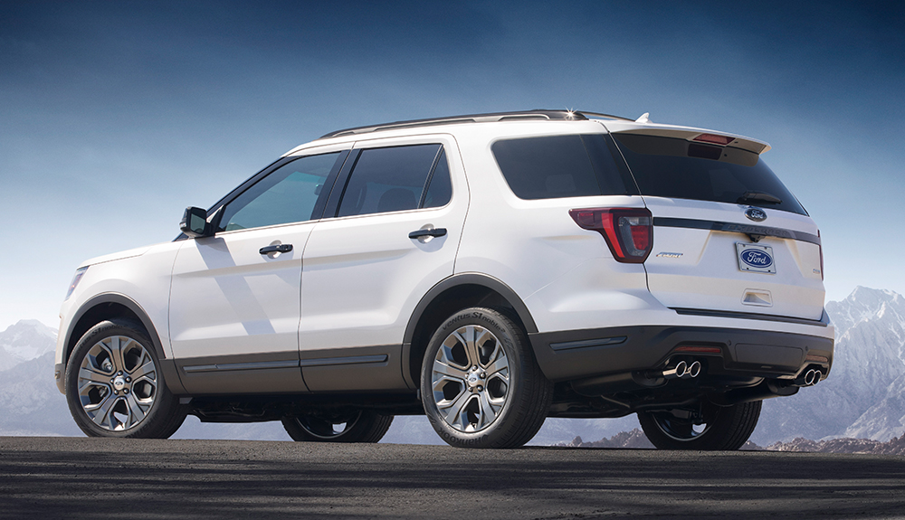 Rear side profile of gleaming white 2018 Ford Explorer parked at high altitude near snowy mountaintops
