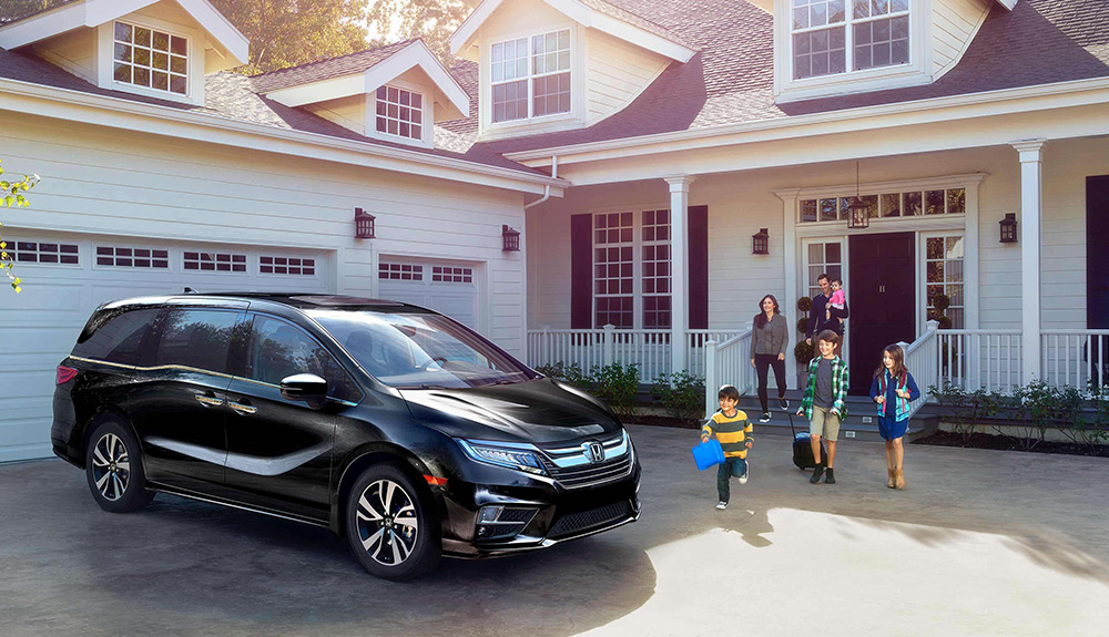 Black 2018 Honda Odyssey parked outside of a house with small children eager to get on board