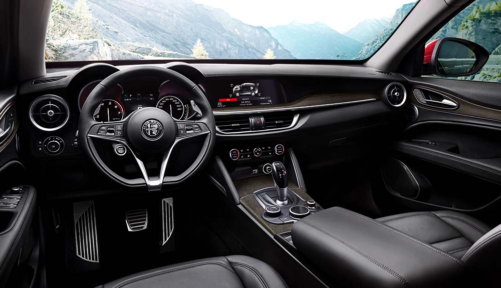 Interior shot of 2018 Alfa Romeo Stelvio with dark leather seats and gorgeous mountain view out the front dashboard