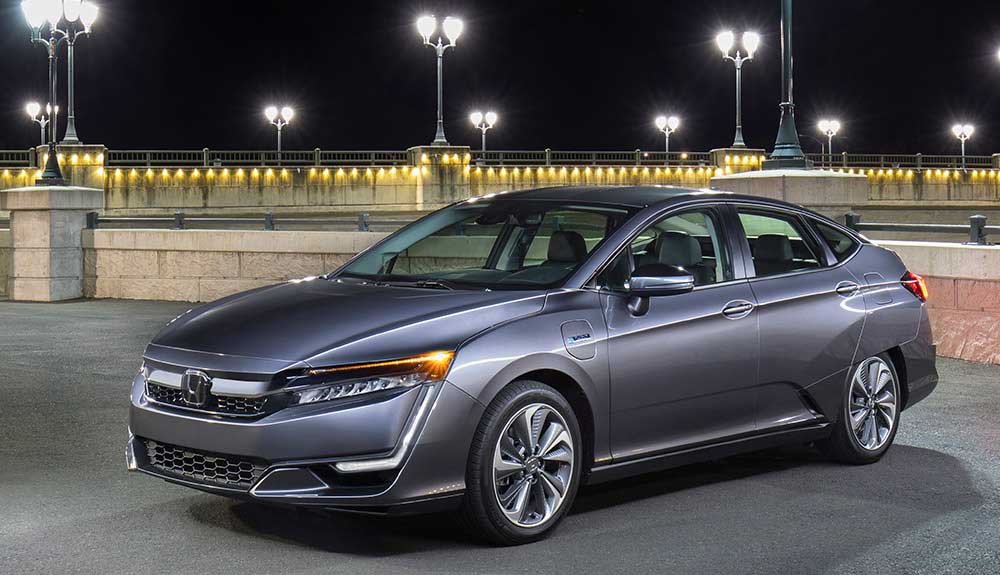 Dark silver 2018 Honda Clarity parked outside with brick fence and streetlights in background