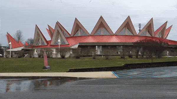 Short GIF of red Chrysler 300S AWD driving by red building with slanted rooftops