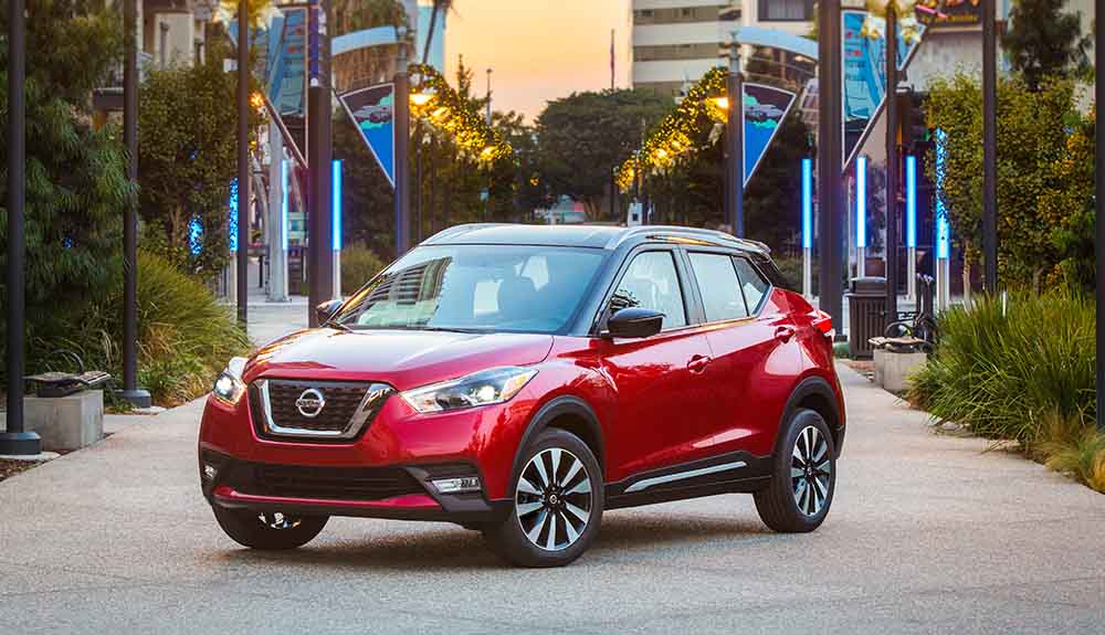 Red Nissan Kicks crossover parked in front of high rise buildings