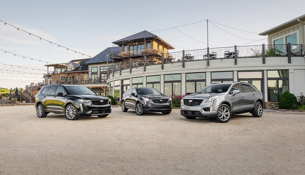 Three grey Cadillac XT6 vehicles are parked outside a restaurant