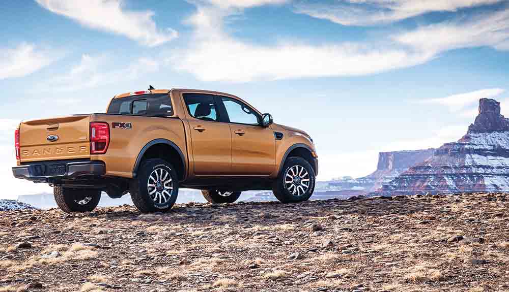 Orange Ford Ranger pickup truck against dramatic purple rock formation
