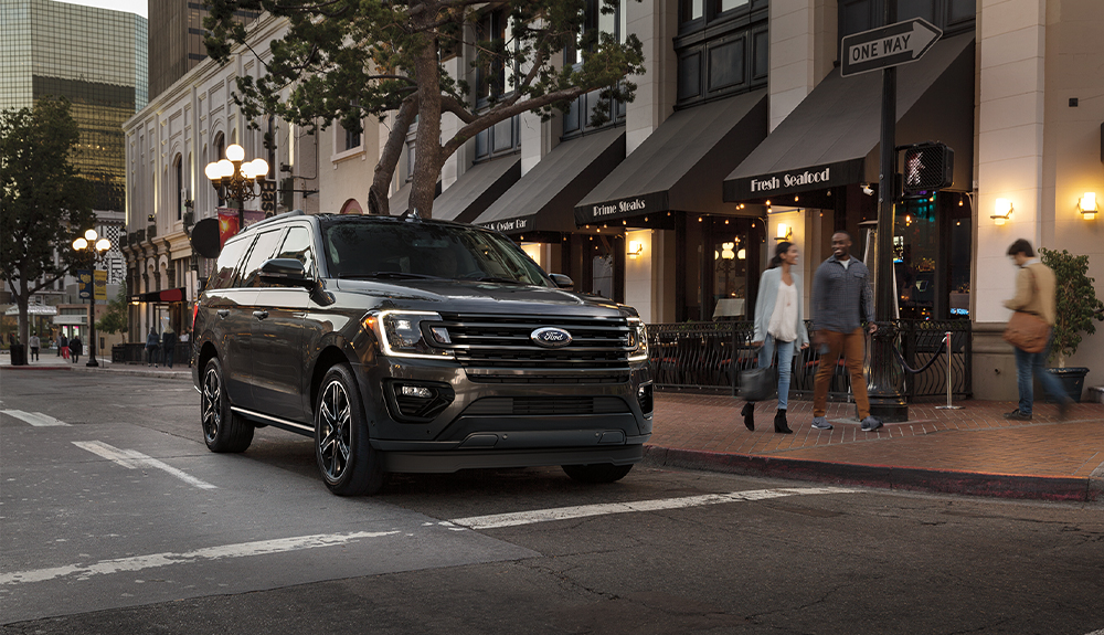 A black Ford Expedition drives through city streets.