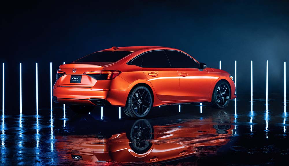 An orange 2022 Honda Civic is shown in an empty parking lot at night