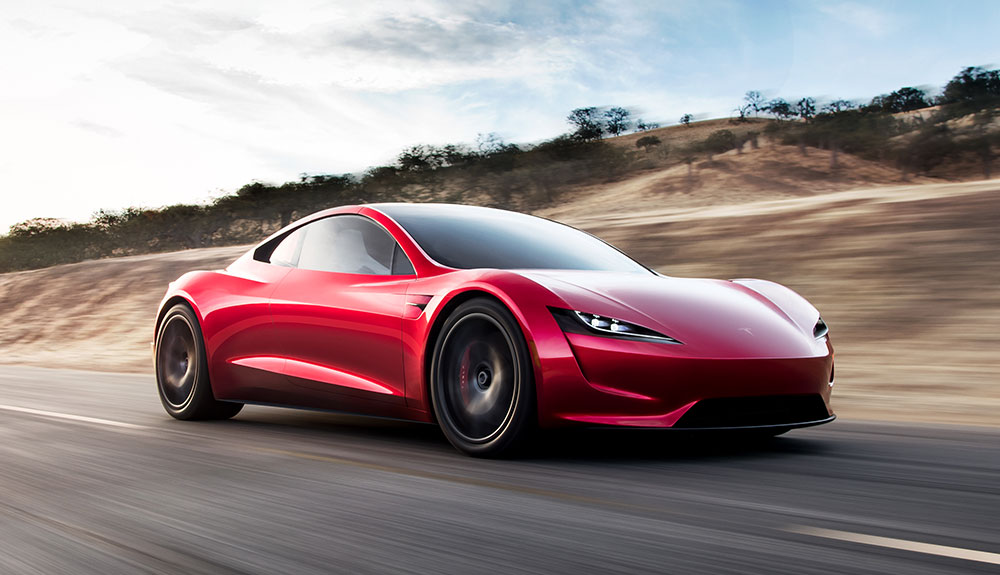 Sleek and sporty red Tesla Roadster speeding down a rural road, the background blurry indicating speed