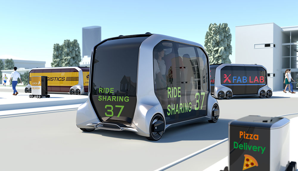 Boxy and futuristic Toyota e-Palette  with LED screen reading Ride Sharing 37 driving down grey laneway with LED signs advertising storefront in matching font
