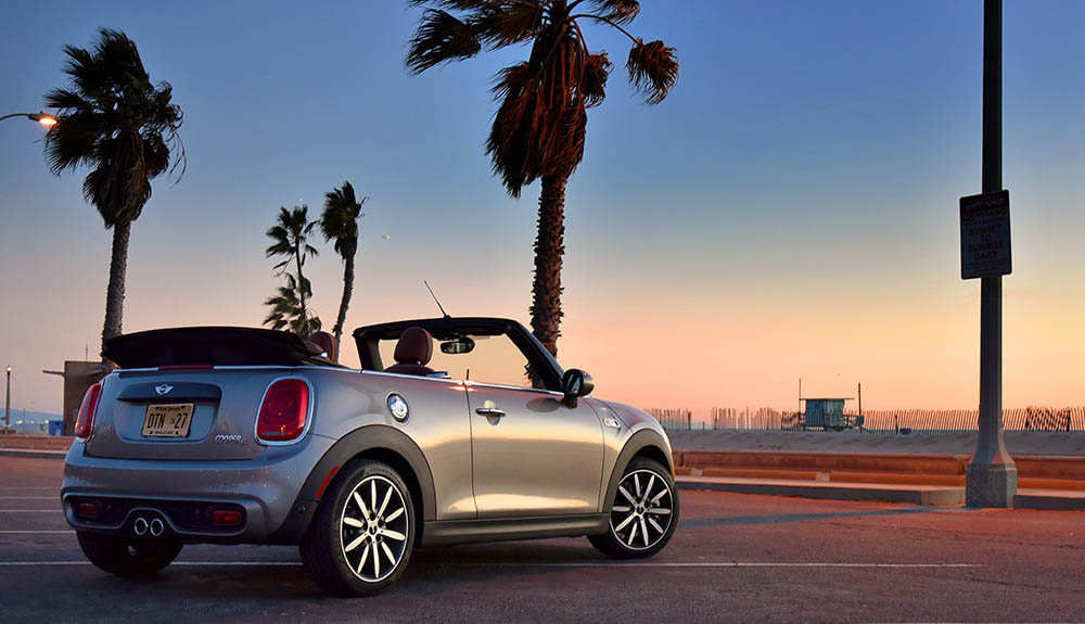 Adorable Mazda Fiat 124 Spider with the roof down facing Venice Beach during sunset