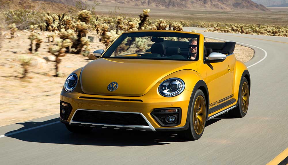 Metallic mustard yellow Volkswagen Beetle taking corners in the desert