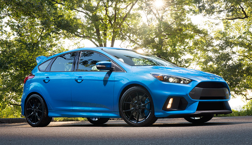 Shiny and cheerful bright blue Ford Focus RS parked on sunny tree-lined street