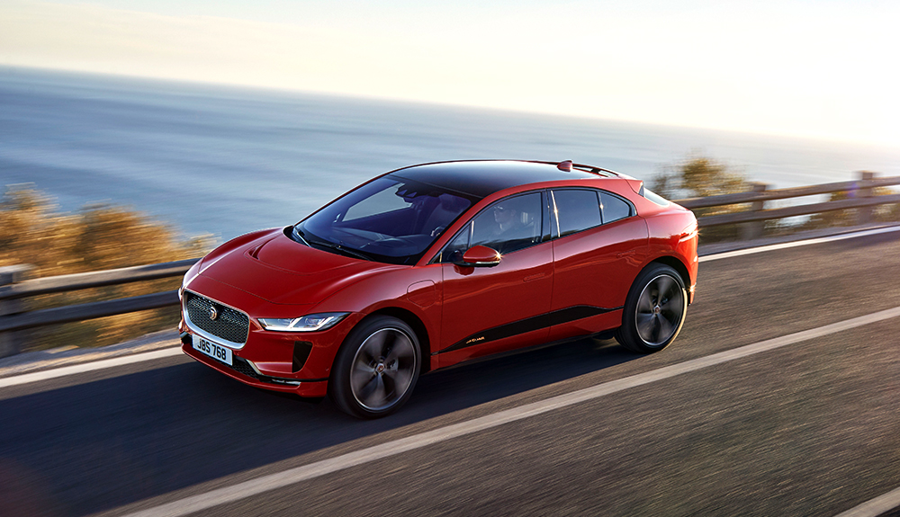 Sporty red Jaguar I-Pace zooming along coastal highway